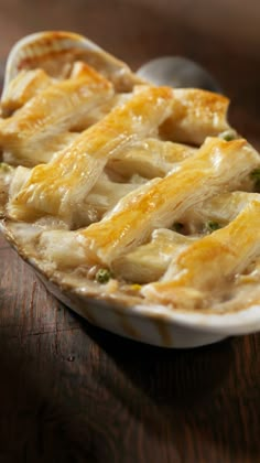 a casserole dish with cheese and broccoli in it on a wooden table