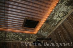 a bathroom with a wooden ceiling and tile flooring on the walls, along with a shower head