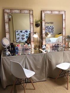 two white chairs sitting in front of a table with mirrors on it