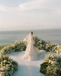 a woman in a wedding dress walking through flowers