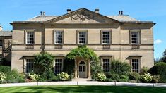 a large house with lots of windows and plants on the front lawn in front of it