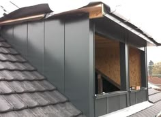 an open window on the side of a building that is being built with metal shingles