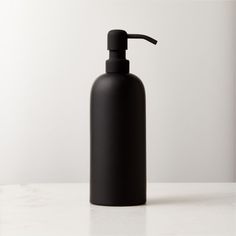 a black soap dispenser on a white counter