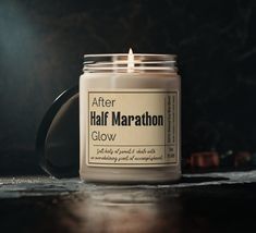 a candle that is sitting on a table next to a black mug with the words after half marathon glow