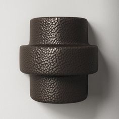 two dark brown leather bracelets hanging on a white wall