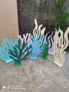 three paper cut out sea creatures sitting next to each other on the cement floor in front of a wall