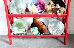 a red shelf with bowls and stuffed animals on it