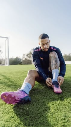 a man sitting on top of a lush green field next to a soccer goalie