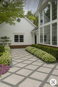 a large white house with many windows and plants in the front garden area on either side