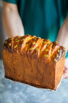 a person holding a loaf of bread with pistachios on the top and bottom