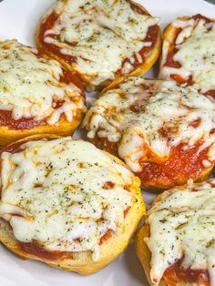 several mini pizzas with cheese and sauce on them sitting on a white platter