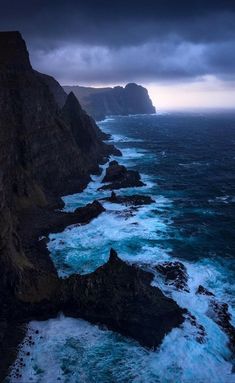 the ocean is blue and choppy with waves crashing against the rocky cliffs in the distance