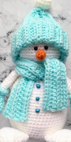 a crocheted snowman wearing a blue hat and scarf