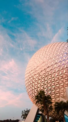 the spaceship shaped building is next to palm trees and blue sky with clouds in the background