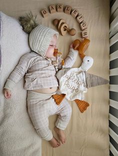 a baby laying on top of a bed next to wooden letters that spell out happy birth