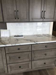 a kitchen with marble counter tops and wooden cabinets in the back drop off area,