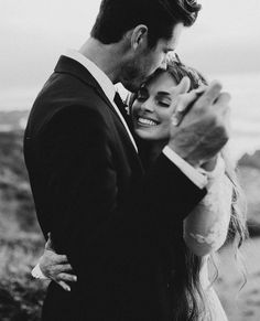 black and white photo of a bride and groom holding their arms around each other as they pose for the camera