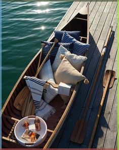 a wooden boat with pillows and blankets on the front is docked at a pier in the water