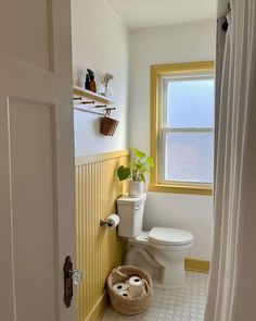 a white toilet sitting in a bathroom next to a window with yellow trim on the walls