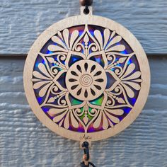 a wooden clock hanging from the side of a building with a colorful design on it