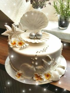 there is a white cake with shells and flowers on it, along with other decorations