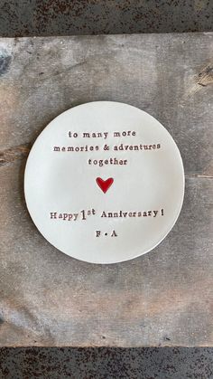 a white plate with a red heart on it that says to many more memories & adventures together happy 1st anniversary