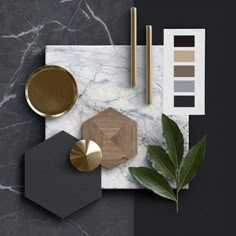 an assortment of items on top of a marble table with gold accents and greenery