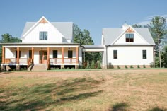 two large white houses sitting on top of a lush green field