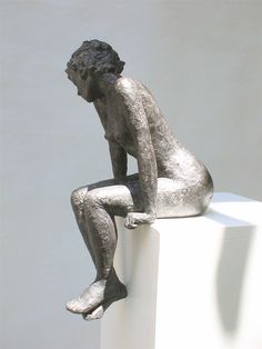 a statue sitting on top of a white block