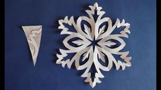 a paper snowflake next to an ornament on a blue background with white lines