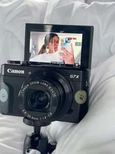 a camera is being used to take pictures on a bed with white sheets and pillows