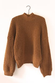 a brown sweater hanging on a white wall