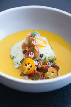 a white bowl filled with soup and garnished with orange slices