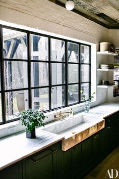 a kitchen with green cabinetry and white counter tops, along with an open window