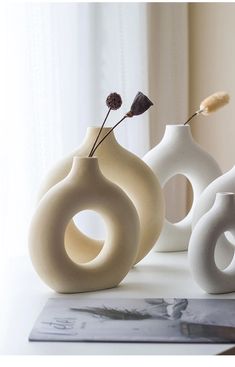 three white vases sitting on top of a table