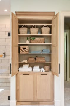 an open cabinet with baskets and towels in it