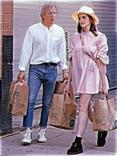 a man and woman walking down the street with bags