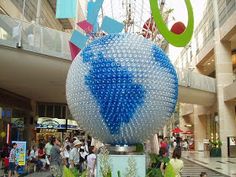 people are walking around an outdoor shopping mall with sculptures in the foreground and onlookers