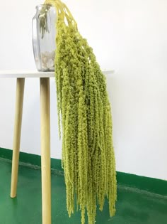 a green plant sitting on top of a white table next to a glass vase filled with water