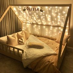 a bed that has some lights on the headboard and pillows in front of it