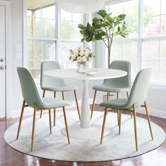 a white table with four chairs around it and a vase filled with flowers on top