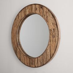 a round wooden mirror hanging on the wall