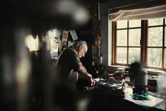 an old man is working on his turntable in the dark room with sunlight coming through the window