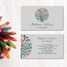 two business cards with colored pencils in the center and an image of a tree