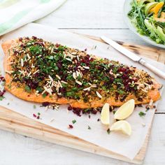 the fish is covered with herbs and garnishes next to a bowl of salad