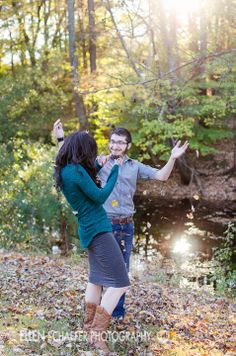 a man and woman standing next to each other in front of a creek with trees