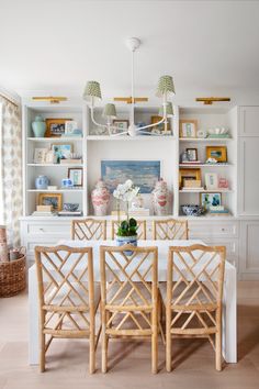 a dining room table with chairs and vases on top of it in front of bookshelves