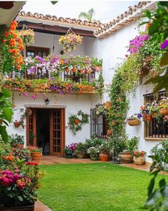 an outside view of a house with flowers on the balconies and potted plants