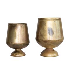 two gold goblets sitting next to each other on a white background, one is empty