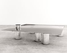 a table that is sitting in the middle of concrete flooring with three legs on each side